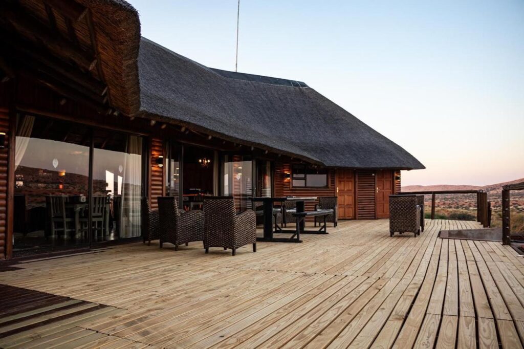 Outdoor deck at Kalahari hunting lodge with rustic wooden furniture and panoramic glass doors